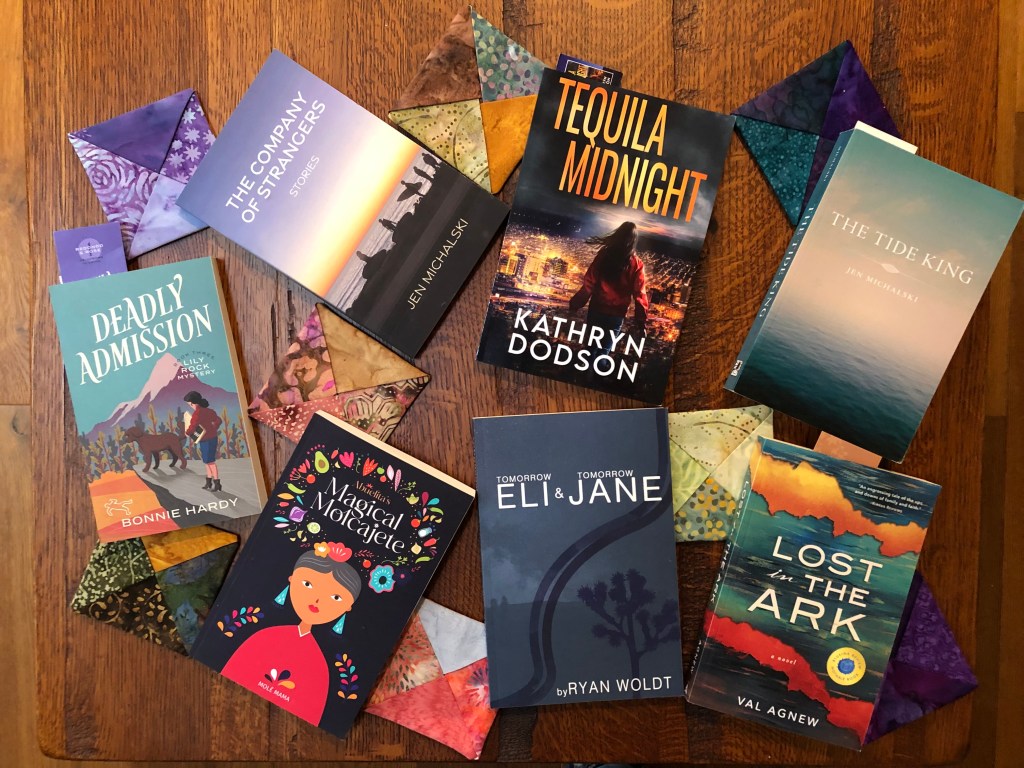 Seven books that I bought at a book fair, laid out on an oak table.