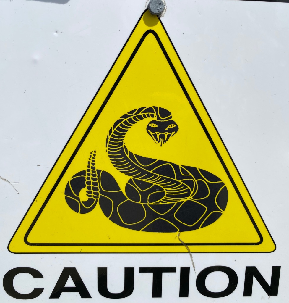 Signage with a rattlesnake and the word “Caution.”